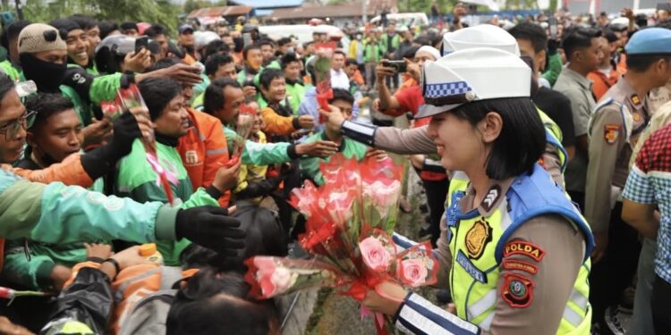 Polwan membagikan bunga kepada ojol di depan Polda Sumatera Utara. (Foto: Humas Polda Sumut)